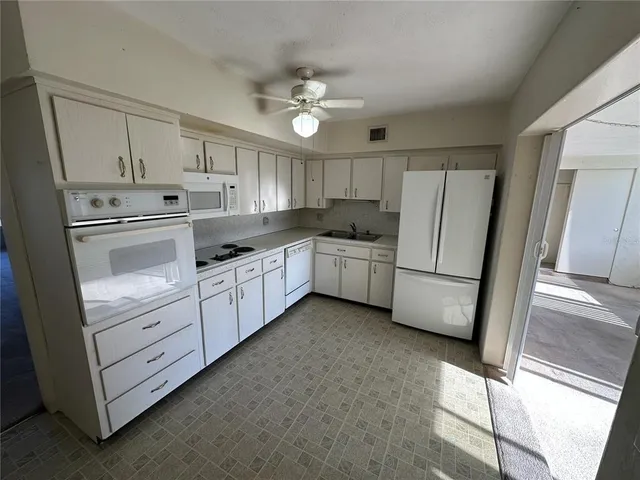 a kitchen with white cabinets and white appliances