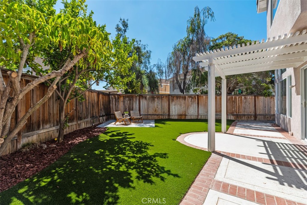 56 Acorn Ridge Rancho Santa Margarita, CA 92688 - Photo 41 of 57 Backyard / Patio: Wide backyard view highlights the shaded patio, brick-accented hardscape, mature trees, and open turf area for flexible outdoor use.