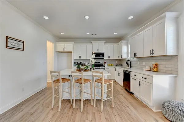 a kitchen with white cabinets stainless steel appliances and dining table