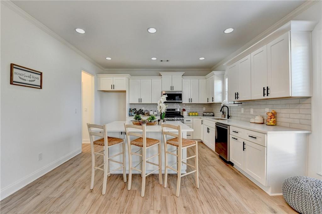 3670 Baxley Ridge Drive Suwanee, GA 30024 - Photo 22 of 64 a kitchen with white cabinets stainless steel appliances and dining table