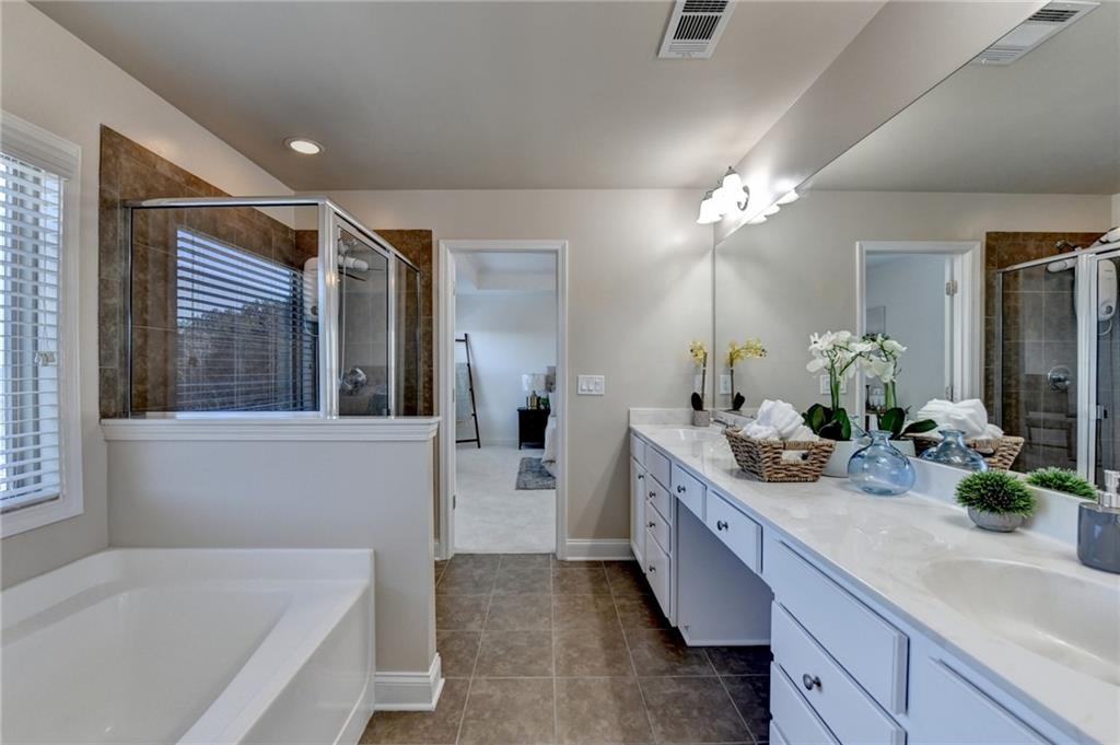 3670 Baxley Ridge Drive Suwanee, GA 30024 - Photo 43 of 64 a spacious en suite bathroom with a double vanity sink tub and mirror
