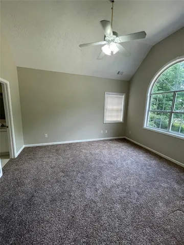 an empty room with windows and chandelier fan
