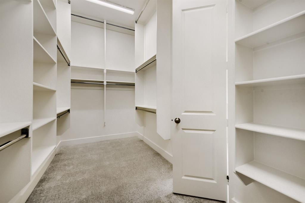 11465 Wulstone Road Fort Worth, TX 76052 - Photo 20 of 27 Spacious walk-in closet featuring extensive built-in shelving, multiple hanging rods, white trim, and light gray carpet flooring