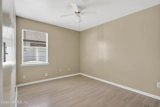 an empty room with a window and a ceiling fan