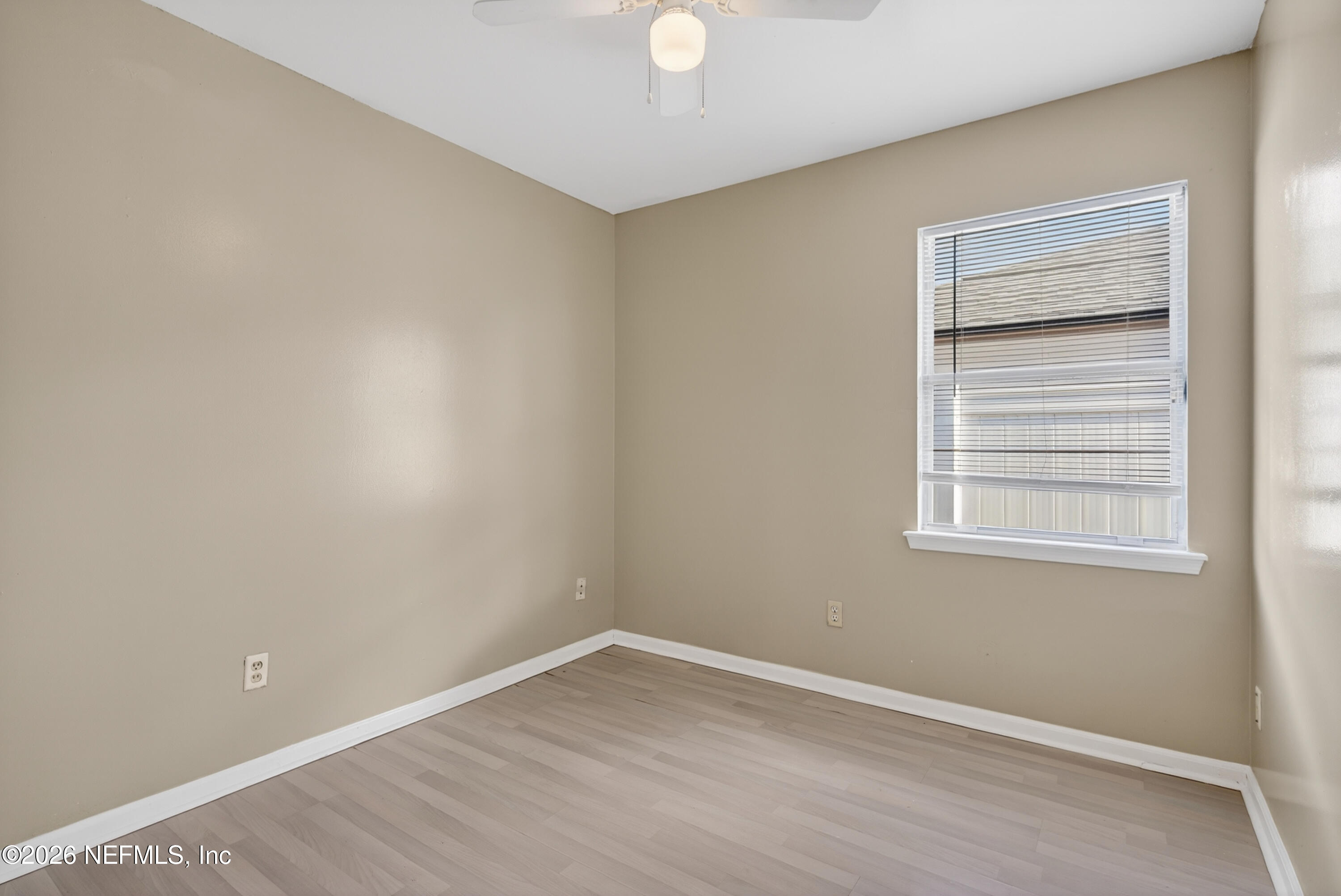 8745 Buzz Court Jacksonville, FL 32216 - Photo 18 of 23 a view of an empty room with wooden floor and a window