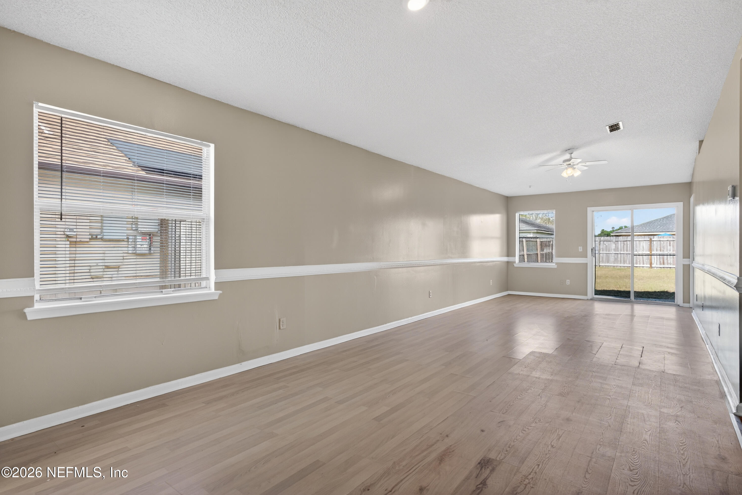 8745 Buzz Court Jacksonville, FL 32216 - Photo 5 of 23 a view of an empty room with wooden floor and a window