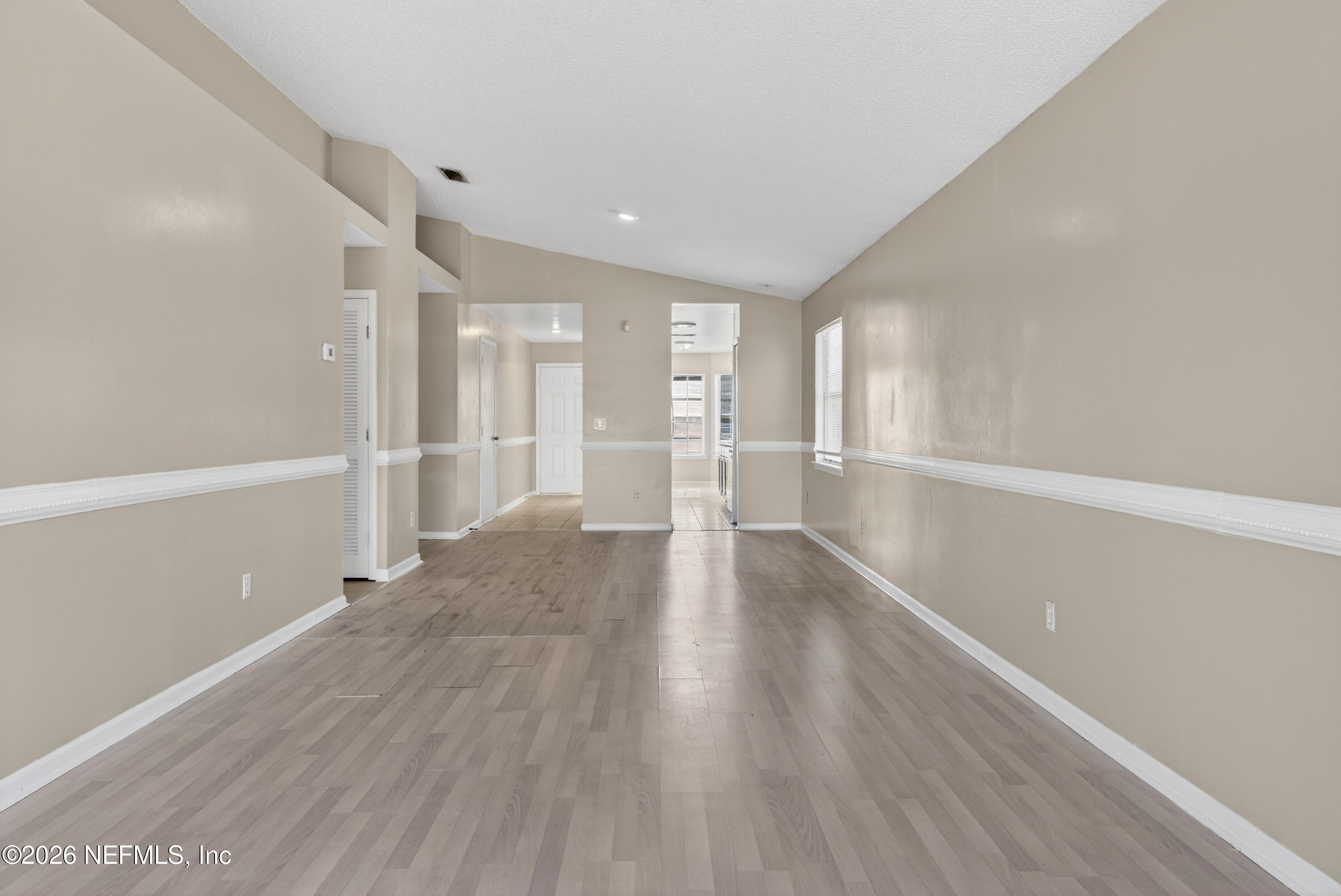 8745 Buzz Court Jacksonville, FL 32216 - Photo 6 of 23 a view of an empty room with wooden floor kitchen view and a window