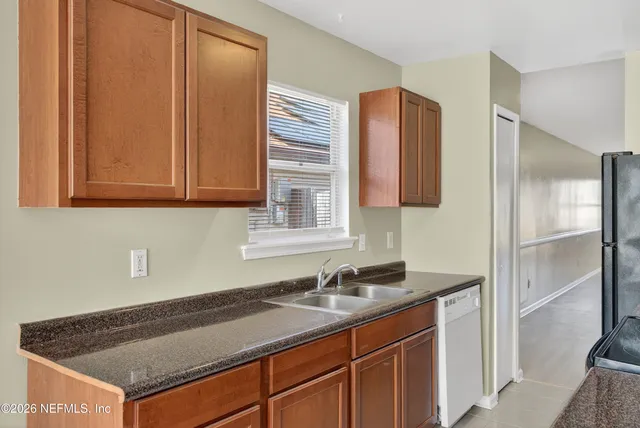 a kitchen with granite countertop a sink cabinets and stainless steel appliances