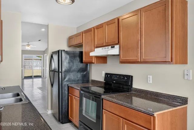 a kitchen with stainless steel appliances granite countertop a refrigerator a stove and a sink with granite countertops