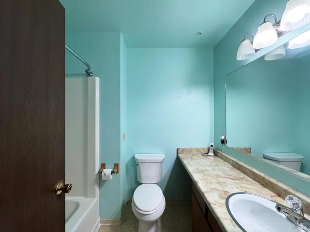 a bathroom with a granite countertop toilet sink and mirror
