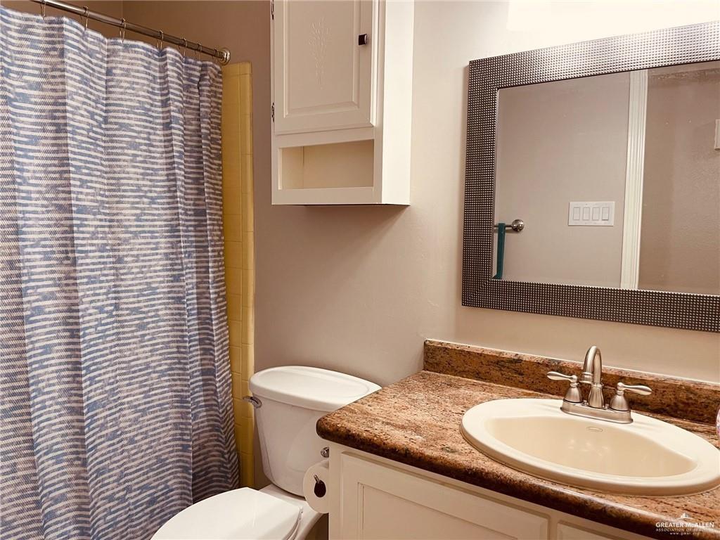 1206 Bluebird Avenue McAllen, TX 78504 - Photo 12 of 20 a bathroom with a granite countertop toilet a sink and a mirror