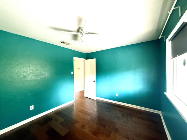 a view of empty room with window and wooden floor