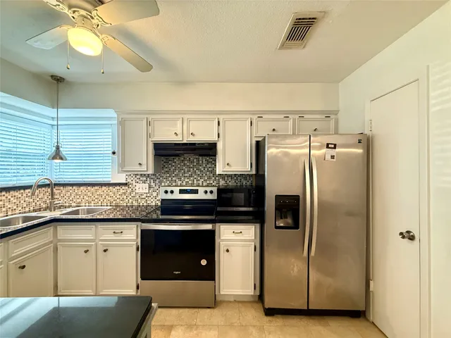 a kitchen with granite countertop a refrigerator and a sink
