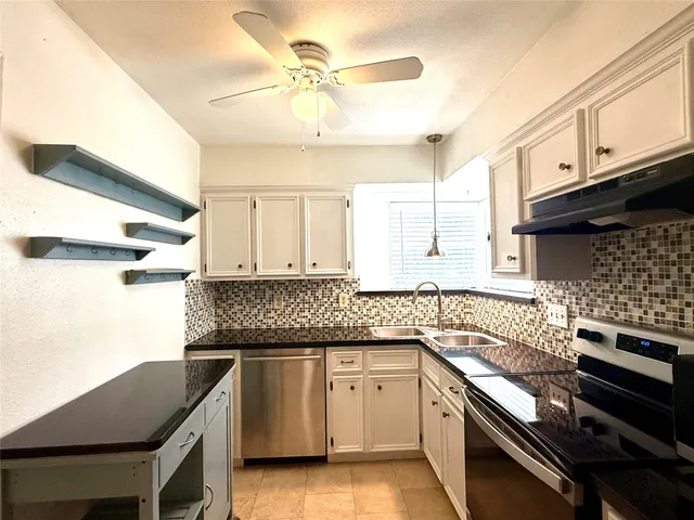 a kitchen with granite countertop a sink a stove and cabinets