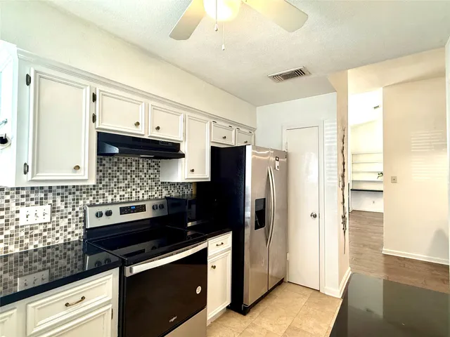 a kitchen with granite countertop a refrigerator stove and sink