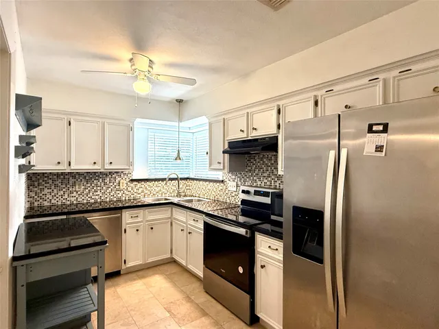 a kitchen with stainless steel appliances granite countertop a sink a stove a refrigerator cabinets and a dining table