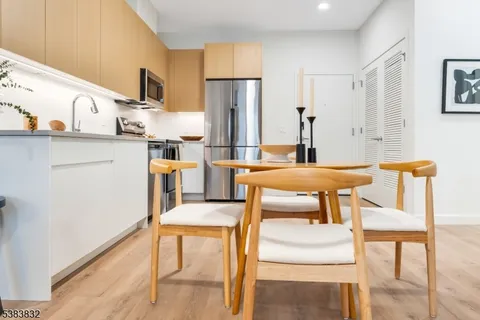 a kitchen with stainless steel appliances kitchen island granite countertop a table chairs and a refrigerator