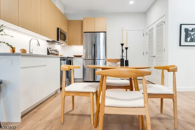 a kitchen with stainless steel appliances kitchen island granite countertop a table chairs and a refrigerator