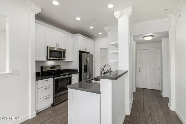 a kitchen with stainless steel appliances a stove top oven a sink dishwasher a refrigerator and cabinets with wooden floor