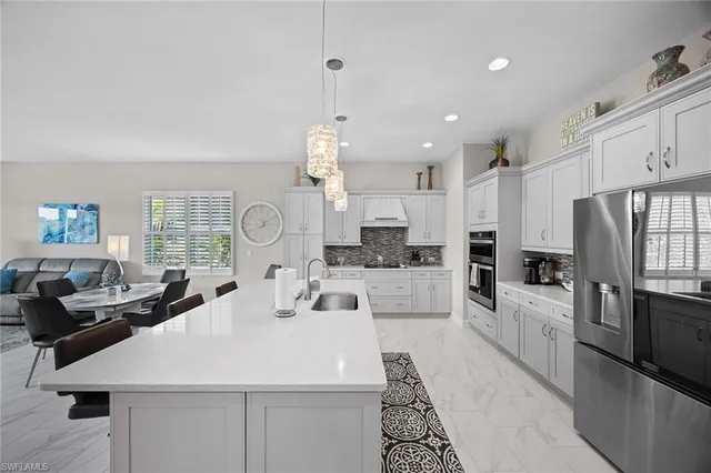 a large white kitchen with a large window and stainless steel appliances