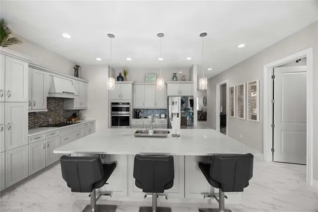 a kitchen with stainless steel appliances kitchen island granite countertop a dining table chairs refrigerator and microwave