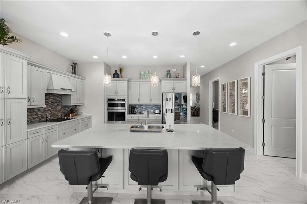 7781 Hawthorne Drive, Unit 3204 Naples, FL 34113 - Photo 18 of 50 a kitchen with stainless steel appliances kitchen island granite countertop a dining table chairs refrigerator and microwave