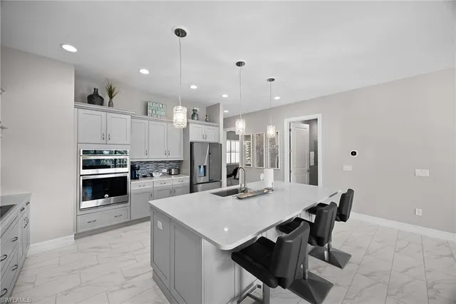 a kitchen with a refrigerator a stove a sink and a dining table with wooden floor