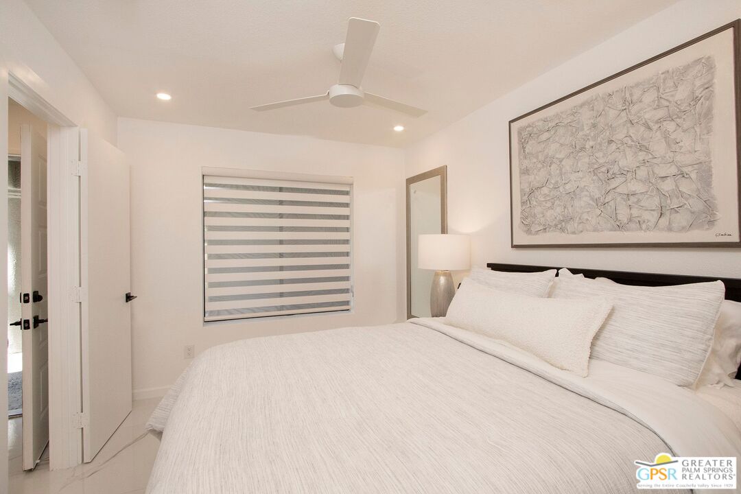 1100 East Amado Road, Unit 13C1 Palm Springs, CA 92262 - Photo 23 of 36 a bedroom with a large bed and a painting on the wall