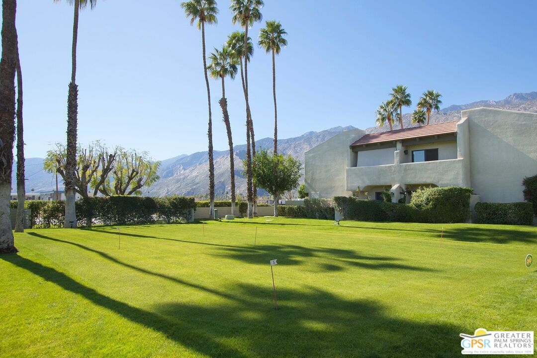 1100 East Amado Road, Unit 13C1 Palm Springs, CA 92262 - Photo 35 of 36 a view of a house with a big yard and palm trees