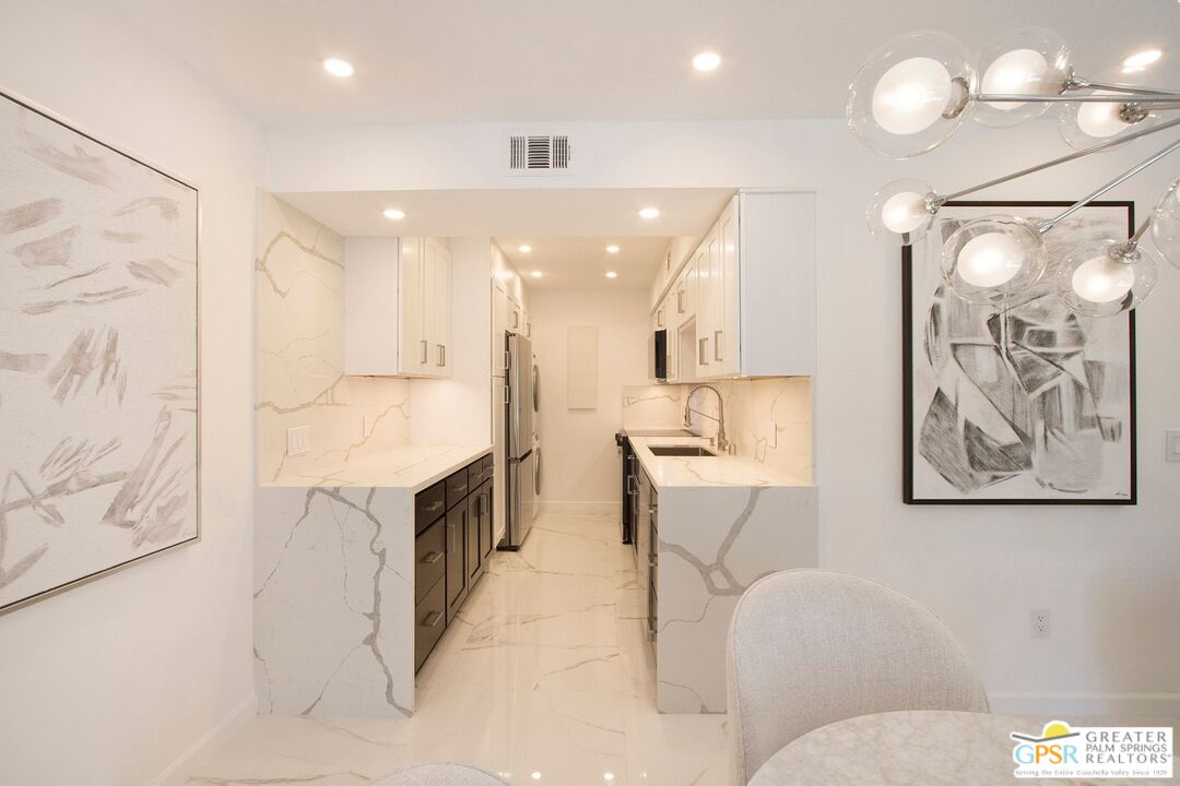 1100 East Amado Road, Unit 13C1 Palm Springs, CA 92262 - Photo 6 of 36 a large bathroom with a large mirror vanity and toilet