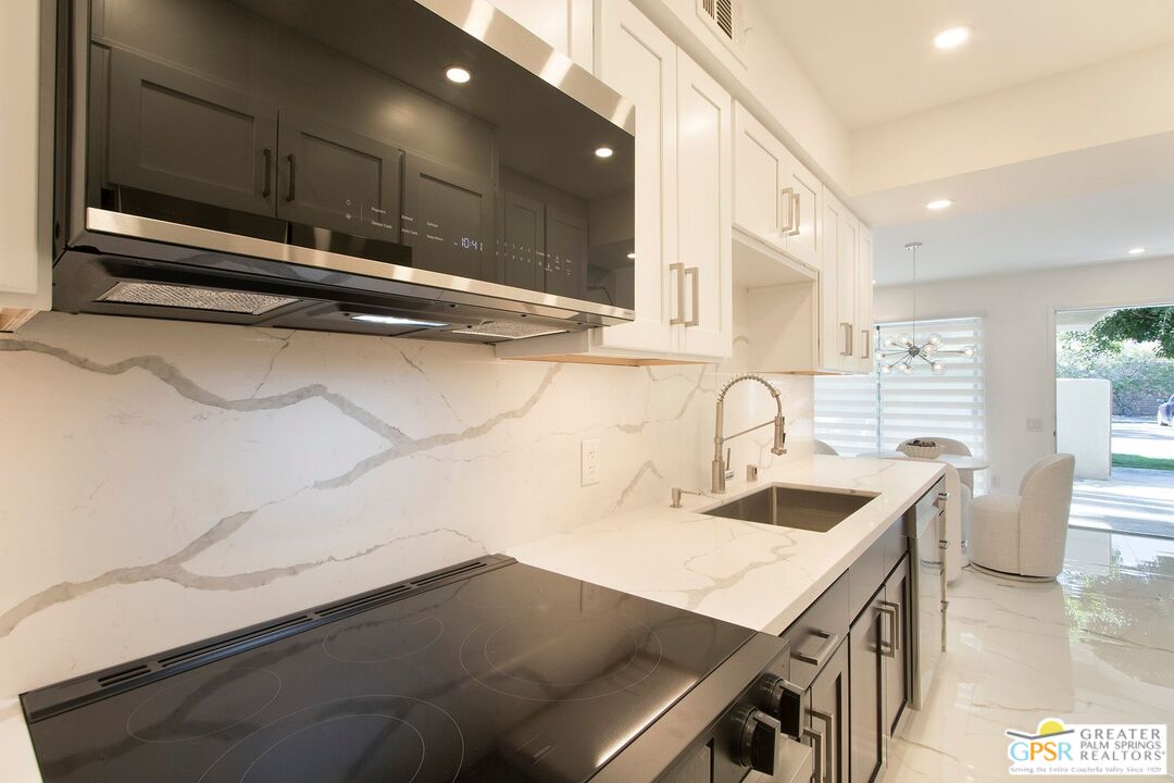 1100 East Amado Road, Unit 13C1 Palm Springs, CA 92262 - Photo 10 of 36 a kitchen with kitchen island a sink appliances and cabinets