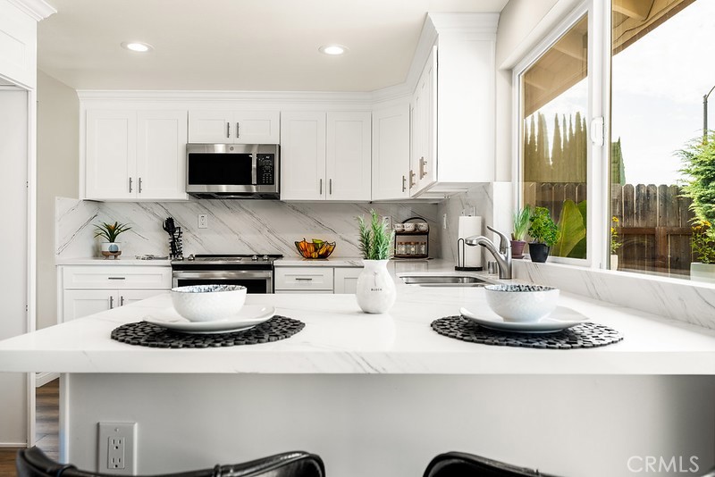 14331 Fernbrook Drive Tustin, CA 92780 - Photo 16 of 35 a kitchen with kitchen island granite countertop a stove a sink and a white cabinets