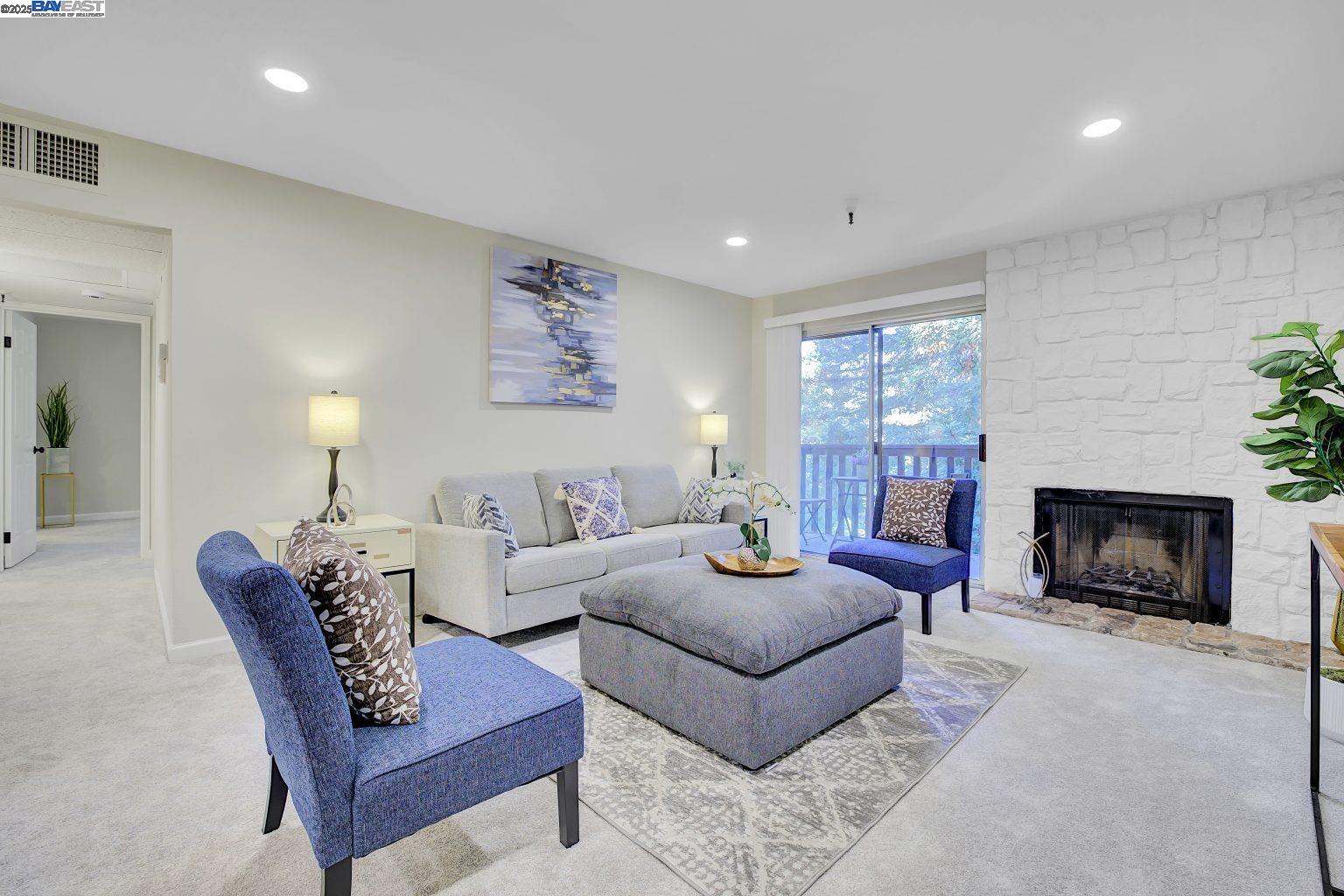 a living room with furniture a fireplace and a large window
