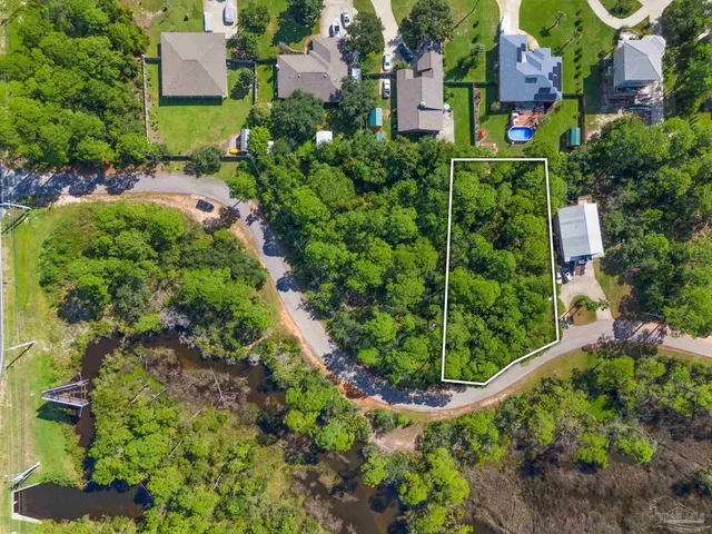an aerial view of residential house with outdoor space and trees all around
