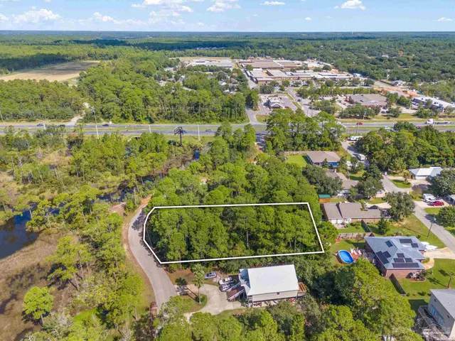an aerial view of residential house with outdoor space and trees all around
