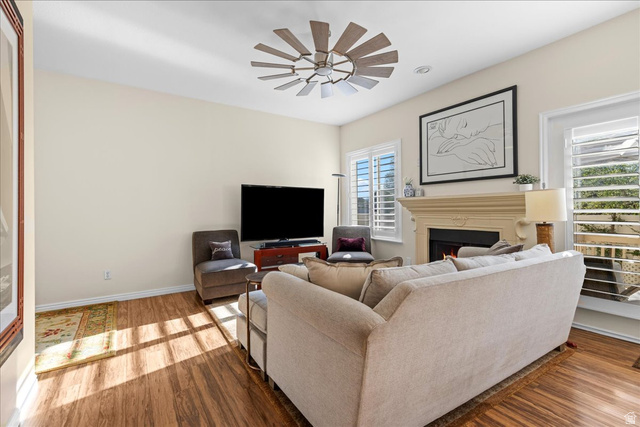 7824 South Sequoia Tree Lane Sandy, UT 84094 - Photo 6 of 43 Living room featuring wood finished floors, ceiling fan, and a warm lit fireplace