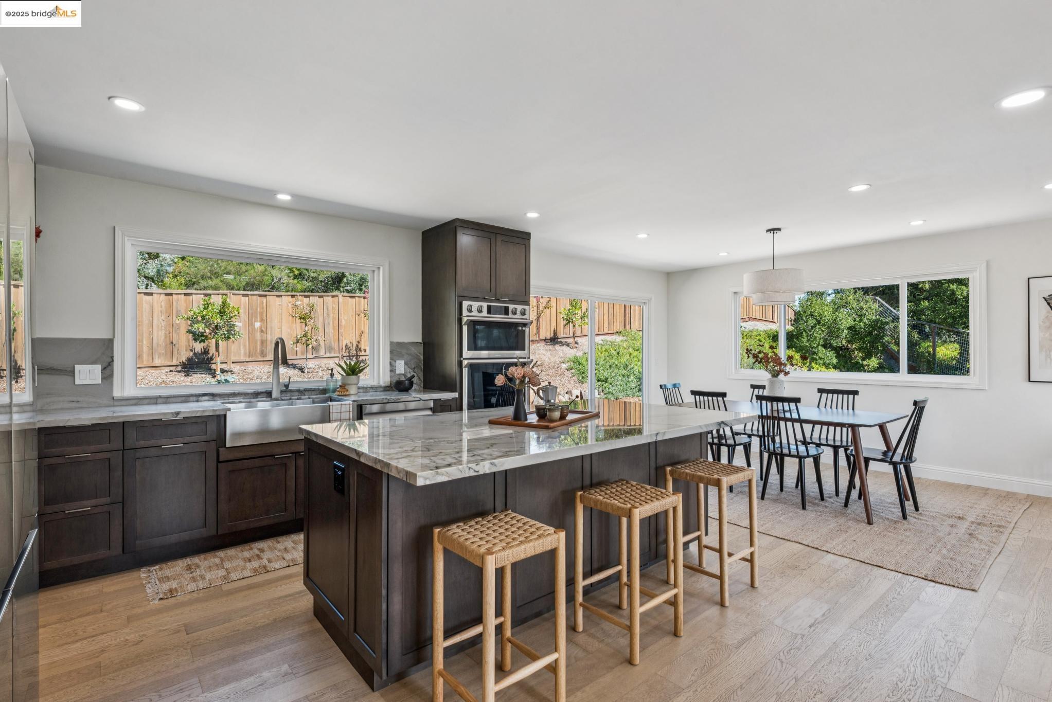 9 Yarmouth Court Oakland, CA 94619 - Photo 12 of 54 Kitchen with dark brown cabinets, light stone countertops, light wood finished floors, a kitchen breakfast bar, and recessed lighting