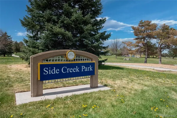 a sign of golf club on a wall under a tree