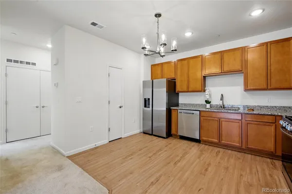 a kitchen with stainless steel appliances granite countertop a refrigerator a sink dishwasher a stove with wooden cabinets and floor