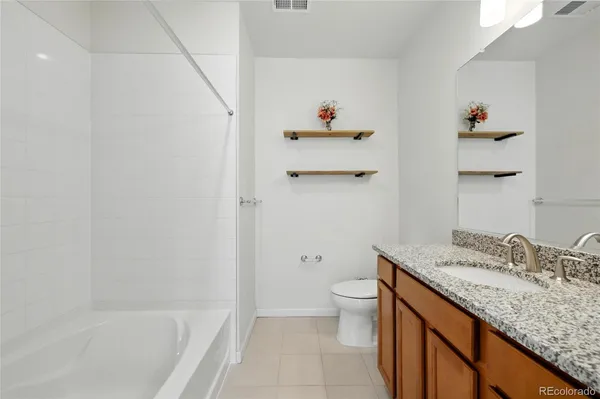 a bathroom with a granite countertop sink a toilet and bathtub