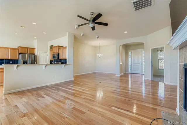 a view of a livingroom with kitchen appliances and a ceiling fan