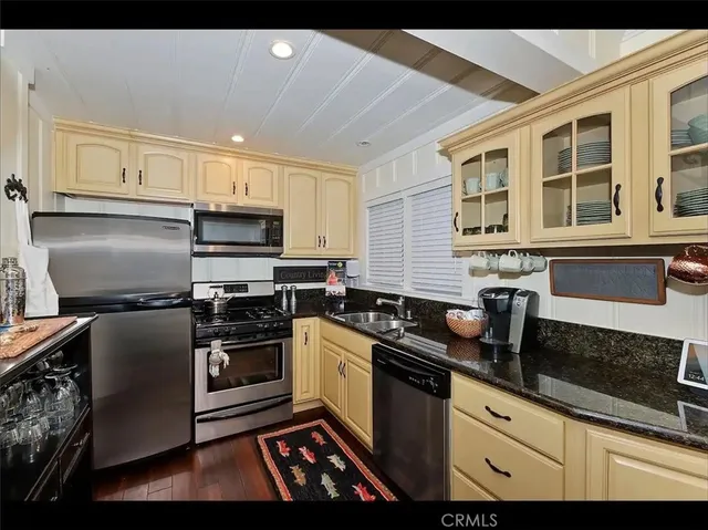 a kitchen with granite countertop a sink stainless steel appliances and cabinets