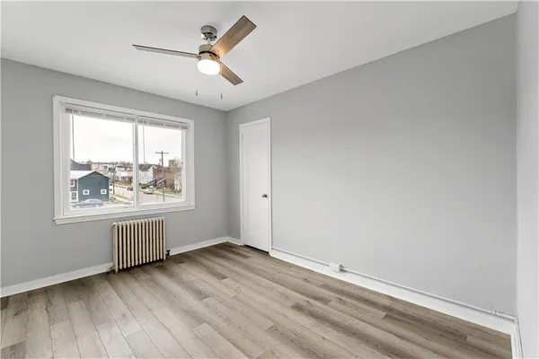 an empty room with wooden floor and ceiling fan