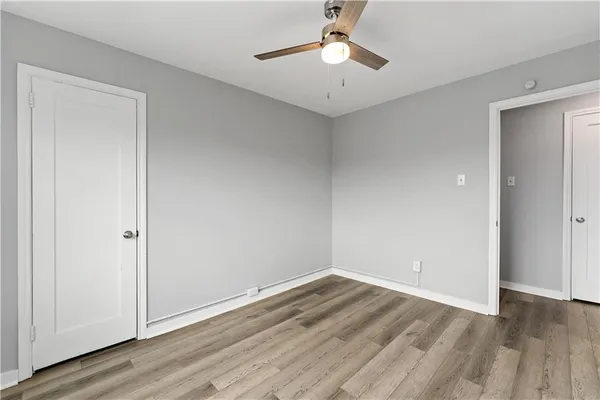 an empty room with wooden floor chandelier fan and windows