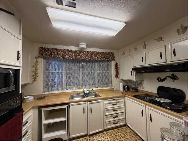 a kitchen with granite countertop a stove sink and cabinets
