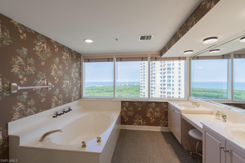 6825 Grenadier Boulevard, Unit 1505 Naples, FL 34108 - Photo 19 of 35 a bathroom with a large tub a double vanity sink and large window
