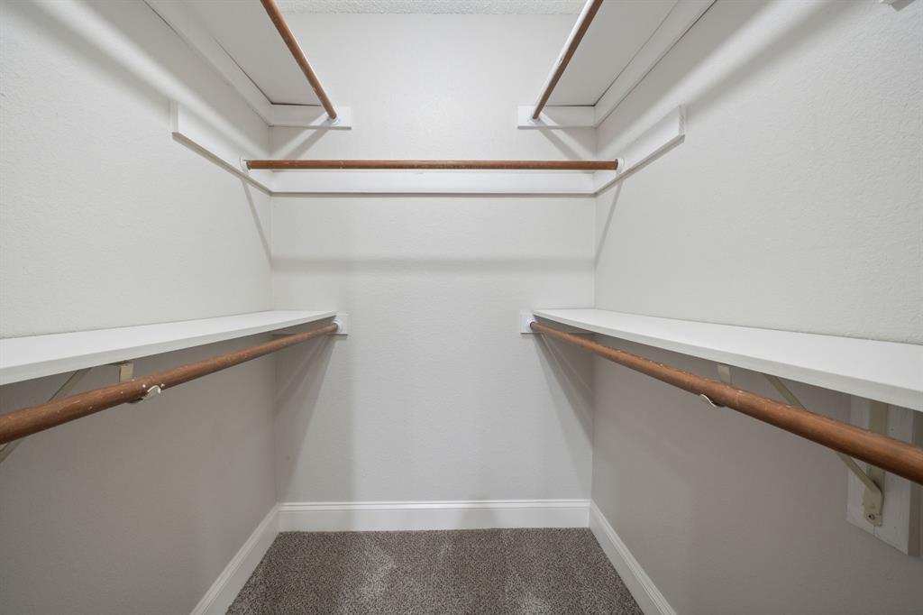 310 Valley Spring Drive Arlington, TX 76018 - Photo 17 of 24 Walk-in closet with carpet flooring, white walls, and built-in shelving with hanging rods