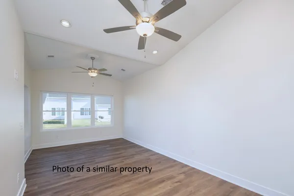 an empty room with wooden floor ceiling fan and windows