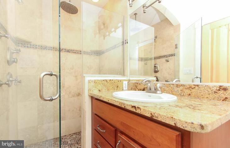 3403 Dillon Street Baltimore, MD 21224 - Photo 15 of 30 a bathroom with a granite countertop sink vanity mirror and shower