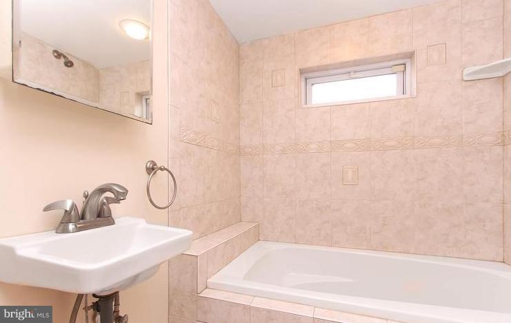 3403 Dillon Street Baltimore, MD 21224 - Photo 9 of 30 a bathroom with a sink a mirror and a shower